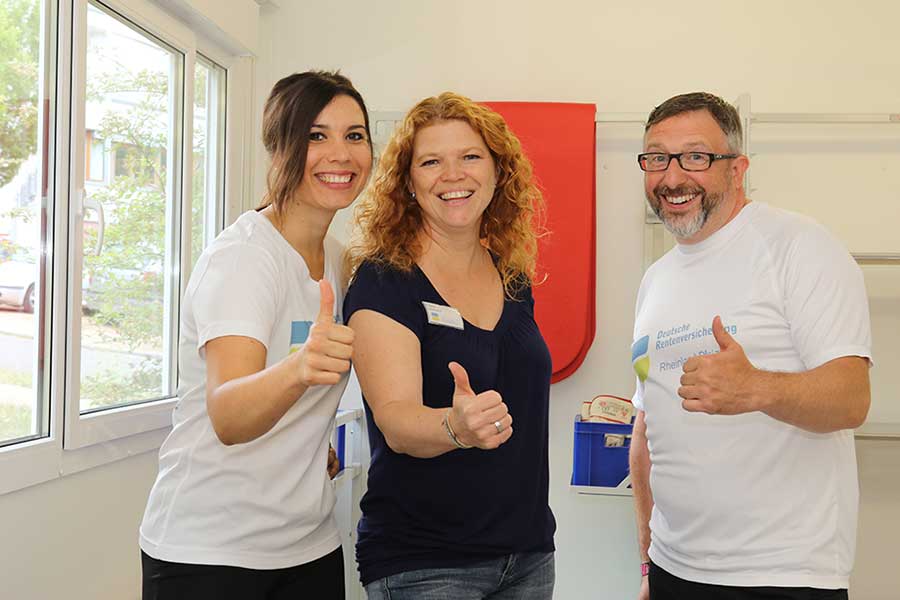 Zwei Frauen und ein Mann lachen in die Kamera und halten die Daumen hoch Zwei Frauen und ein Mann lachen in die Kamera und halten die Daumen hoch