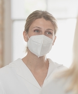 Frau mit Maske spricht mit blonder Frau im Vordergrung Frau mit Maske spricht mit blonder Frau im Vordergrung