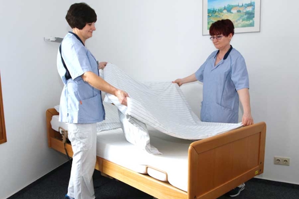 Zwei Frauen beziehen ein Patientenbett