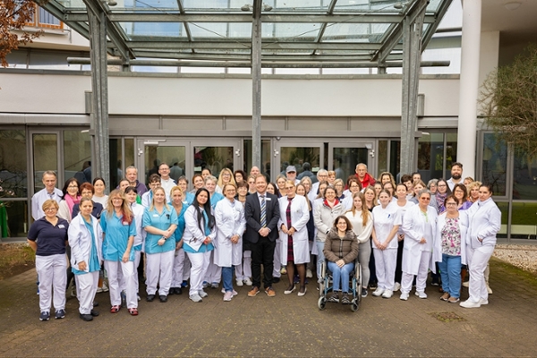Viele Mitarbeiterinnen und Mitarbeiter stehen zum Gruppenfoto vor der Tür zum Außenbereich Viele Mitarbeiterinnen und Mitarbeiter stehen zum Gruppenfoto vor der Tür zum Außenbereich