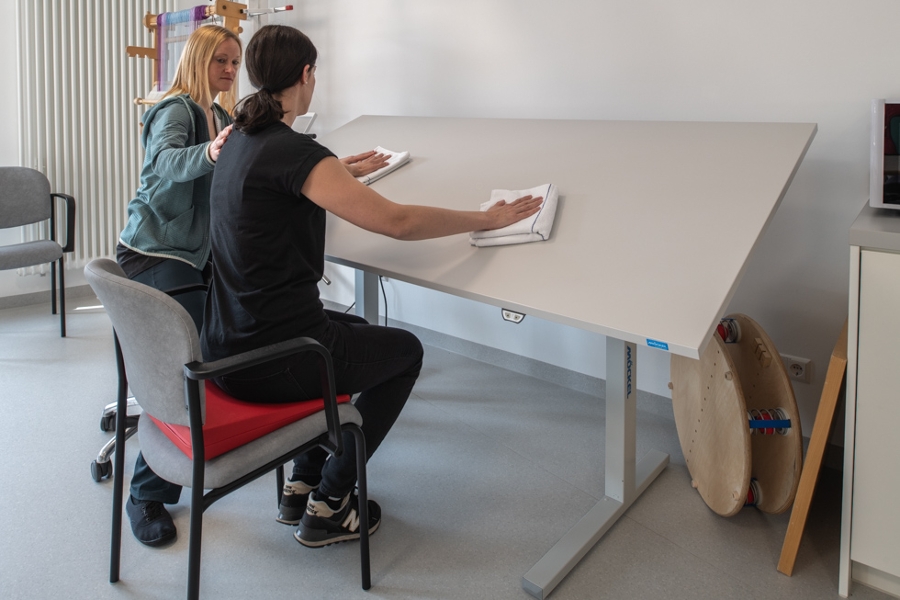 Patientin wischt über eine Tischplatte Patientin wischt über eine Tischplatte